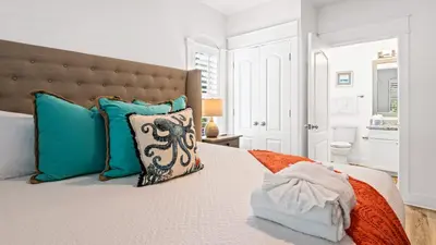 a bedroom with a large bed with blue pillows at Villas at Seagrove A101 - Sunshine Sabbatical in Santa Rosa Beach