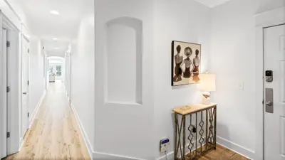 a hallway with white walls and a table with a lamp at Villas at Seagrove A101 - Sunshine Sabbatical in Santa Rosa Beach