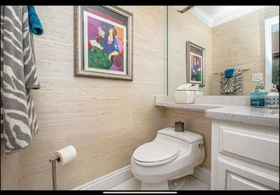 a bathroom with a toilet and a painting on the wall at Dancing Dolphins, Watercrest 1803,1804 in Panama City Beach