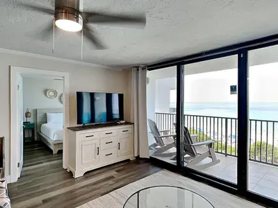 a living room with a television and a balcony at One Seagrove Place #507 in Santa Rosa Beach