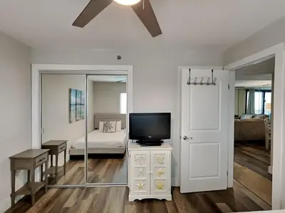 a living room with a tv and a mirror at One Seagrove Place #507 in Santa Rosa Beach