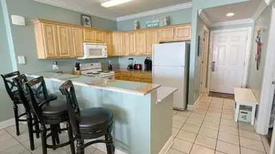 a kitchen with wooden cabinets and a white refrigerator at Tropic Winds 2007 in Panama City Beach