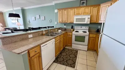 a kitchen with wooden cabinets and a white refrigerator at Tropic Winds 2007 in Panama City Beach