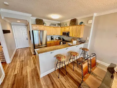 a kitchen with a counter and stools in it at Tropic Winds 1208 in Panama City Beach