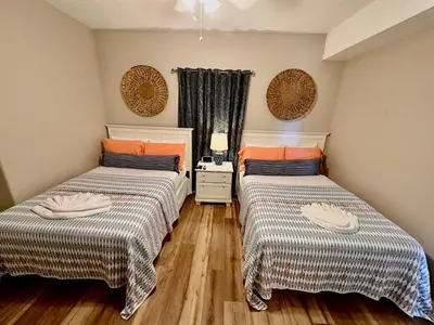 two beds in a room with wooden floors at Tropic Winds 1208 in Panama City Beach