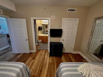a bedroom with two beds and a hallway with two doors at Tropic Winds 1208 in Panama City Beach