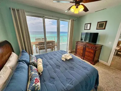 a bedroom with a blue bed and a couch and a television at Tropic Winds 701 in Panama City Beach