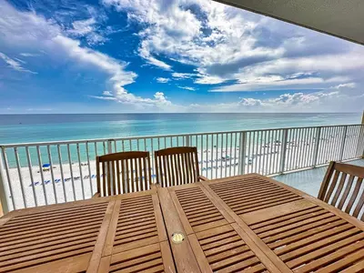a wooden table and chairs on a balcony with the beach at Tropic Winds 701 in Panama City Beach