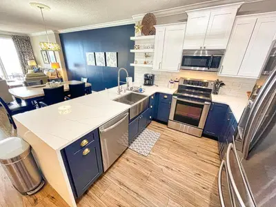 a large kitchen with blue cabinets and a counter top at Tropic Winds 2005 in Panama City Beach