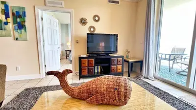 a living room with a tv and a dinosaur on the floor at Tropic Winds 2105 in Panama City Beach