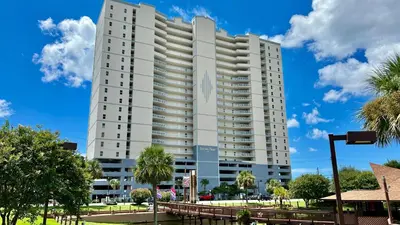 a large white building with palm trees in front of it at Ocean Reef 1407 in Panama City Beach
