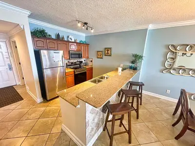 a kitchen with a refrigerator and a counter top at Ocean Reef 1802 in Panama City Beach