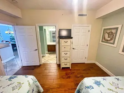 a bedroom with two beds and a dresser with a television at Ocean Reef 1802 in Panama City Beach