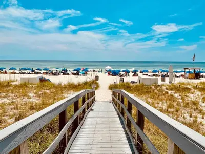 a boardwalk leading to the beach with umbrellas at Ocean Reef 1904 in Panama City Beach