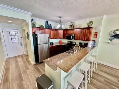 a kitchen with a stainless steel refrigerator and wooden cabinets at Tropic Winds 1904 in Panama City Beach