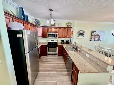 a kitchen with wooden cabinets and a stainless steel refrigerator at Tropic Winds 1904 in Panama City Beach