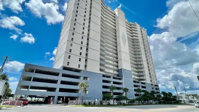 a tall white building with palm trees in front of it at Ocean Reef 1608 in Panama City Beach