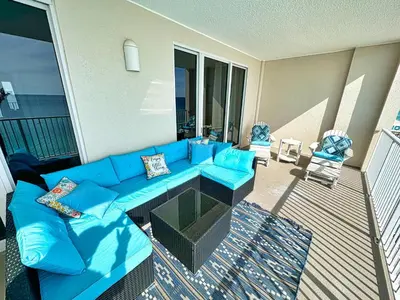 a living room with a blue couch on a balcony at Ocean Reef 1202 in Panama City Beach