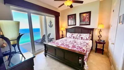 a bedroom with a bed and a balcony with the ocean at Ocean Reef 2101 in Panama City Beach