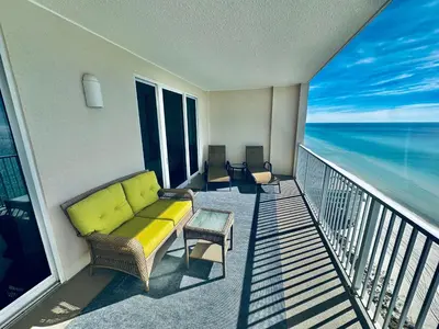 a balcony with a yellow couch on a balcony with the ocean at Ocean Reef 1707 in Panama City Beach