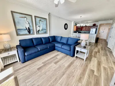 a living room with a blue couch and a kitchen at Tropic Winds 2305 in Panama City Beach