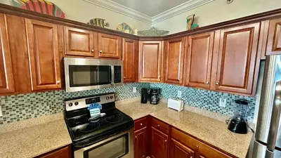a kitchen with wooden cabinets and a stove and microwave at Tropic Winds 2305 in Panama City Beach