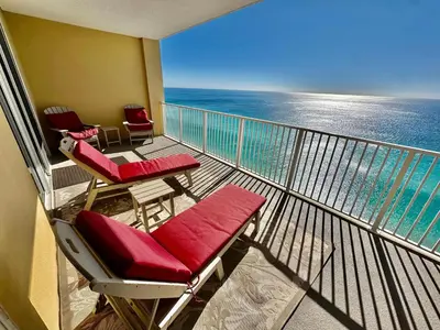 a balcony with chairs and tables and the ocean at Tropic Winds 2305 in Panama City Beach