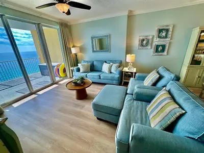 a living room with blue couches and a balcony at Tropic Winds 1705 in Panama City Beach