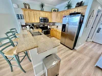 a kitchen with wooden cabinets and a stainless steel refrigerator at Tropic Winds 1705 in Panama City Beach