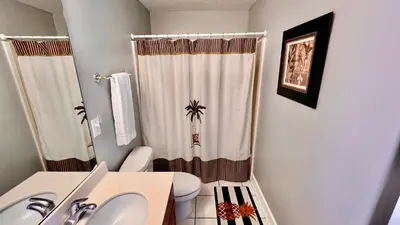 a bathroom with a white toilet and a shower curtain at Ocean Reef 1803 in Panama City Beach
