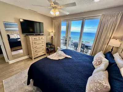a bedroom with a blue bed with a view of the ocean at Tropic Winds 702 in Panama City Beach