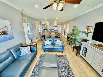 a living room with a blue couch and a tv at Tropic Winds 702 in Panama City Beach