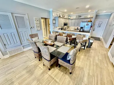 a dining room with a table and chairs and a kitchen at Tropic Winds 702 in Panama City Beach