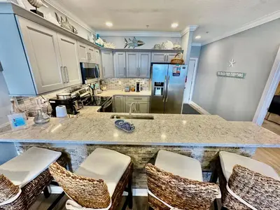a kitchen with a large counter with chairs in it at Tropic Winds 702 in Panama City Beach