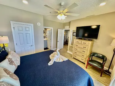 a bedroom with a blue bed and a flat screen tv at Tropic Winds 702 in Panama City Beach