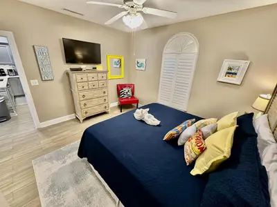 a bedroom with a blue bed with pillows and a tv at Tropic Winds 702 in Panama City Beach