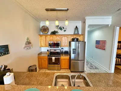 a kitchen with stainless steel appliances and wooden cabinets at Ocean Reef 2303 in Panama City Beach