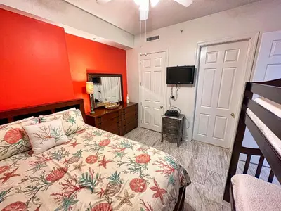 a bedroom with a bed with an orange wall at Ocean Reef 2303 in Panama City Beach