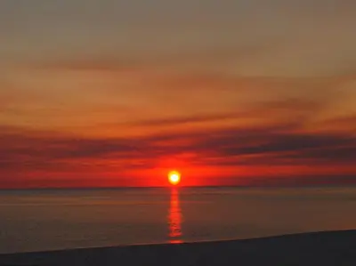 a sunset on the beach with the sun setting at Ocean Reef 2303 in Panama City Beach