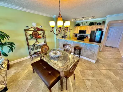 a dining room with a table and chairs and a kitchen at Ocean Reef 703 in Panama City Beach
