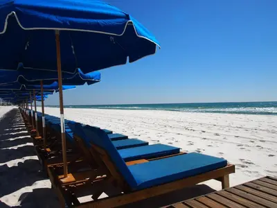 a row of beach chairs with blue umbrellas on the beach at Ocean Reef 1609 in Panama City Beach