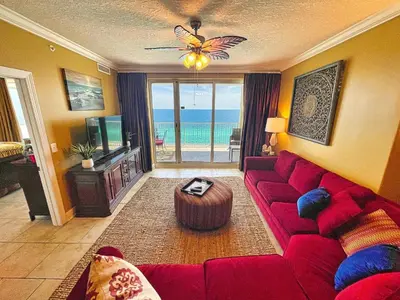 a living room with a red couch and a view of the ocean at Ocean Reef 1609 in Panama City Beach
