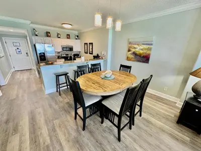 a dining room with a table and chairs and a kitchen at Ocean Reef 606 in Panama City Beach