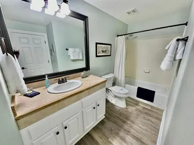 a bathroom with a sink and a toilet and a mirror at Ocean Reef 606 in Panama City Beach