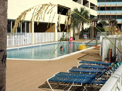 a swimming pool with blue lounge chairs in a building at Ocean Reef 606 in Panama City Beach