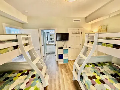 a room with three bunk beds and a tv at Ocean Reef 606 in Panama City Beach