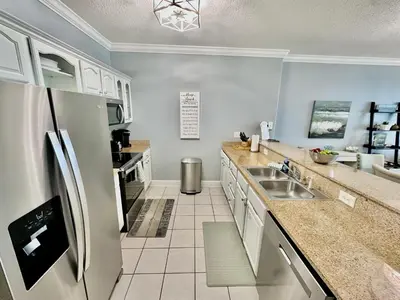 a kitchen with a sink and a refrigerator at Ocean Reef 1006 in Panama City Beach