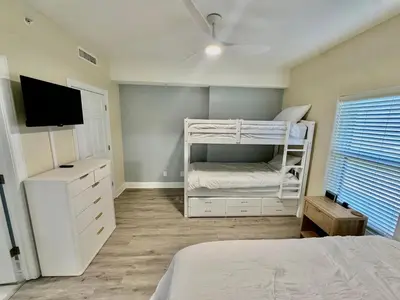 a bedroom with a white bunk bed and a tv at Ocean Reef 1006 in Panama City Beach