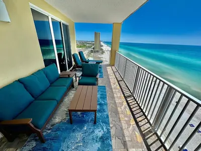 a balcony with a couch and chairs and the ocean at Tropic Winds 1401 in Panama City Beach