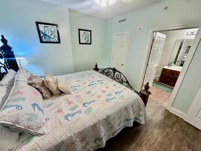 a bedroom with a bed with a comforter on it at Tropic Winds 1401 in Panama City Beach
